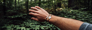 Man showing off his wanderer bracelet in a forest