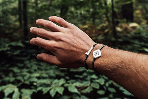 Man showing off his wanderer bracelet in a forest